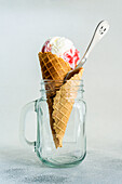 Glass jar with waffle cone filled with cherry ice cream on concrete table