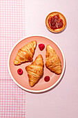 Von oben der Zusammensetzung der plated mit frisch gebackenen süßen Croissants serviert mit Beeren und Marmelade auf rosa Tisch platziert