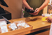 Cropped unrecognizable woman using credit card to pay for goods to vendor in zero waste grocery store