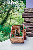 Holzkiste mit verschiedenen Bierflaschen auf dem Tisch im grünen Garten an einem sonnigen Sommertag