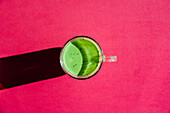 Draufsicht auf ein traditionelles orientalisches Matcha-Getränk für Gesundheit und Energie auf hellrosa Hintergrund