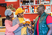Group of African American happy friends clinking glasses with beer while enjoying weekend together in bar
