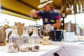 Soft focus of corked small bottles of coffee grains placed on table in country house on blurred background of bartender
