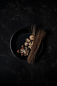 Top view of fresh mushrooms and hard brown noodles on pan for cooking Korean dish Japchae