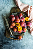 Fresh organic and ripe plum fruits in plate on concrete background