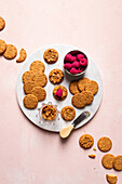 Top view of plates with delicious crispy homemade cookies and fresh raspberries served on table with teapot bowl of seeds