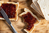 Top view of appetizing crispy toasts with cherry jam served on wooden chopping board