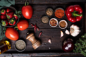 Draufsicht auf frische reife Tomaten und Erdbeeren auf Holztisch mit verschiedenen Gewürzen und Zutaten für Gazpacho-Suppenrezept