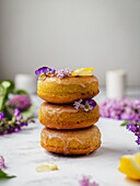 Pile of tasty donuts with fresh lemon pieces and blooming Lavandula flowers on sweet glaze