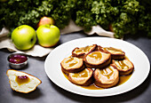 Appetizing crunchy toasts with apple jam served on white plate on table against green plant