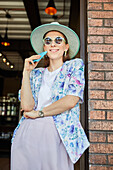 Smiling young female in stylish apparel with cellphone in cafeteria with lamps