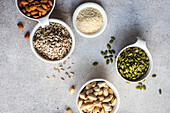 Top view of bowls full of nuts and seeds on concrete background