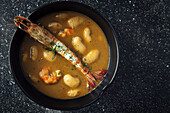 From above of appetizing cream soup with white beans and langoustines served in bowl and placed on marble tabletop in kitchen