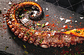 Köstliche gegrillte Oktopus-Tentakel, serviert mit Gewürzen auf einem Holzbrett