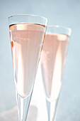 Rose sparkling wine or champagne in crystal glasses on light background in sunny day