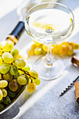 Georgischer Mtsvane-Wein im Glas und frische rohe Trauben auf rustikalem Tisch