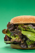 Fresh burger bun with bunch of fresh mesclun leaves as concept of healthy food against green background