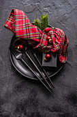 From above ceramic plate setting for Christmas dinner on concrete table on dark background