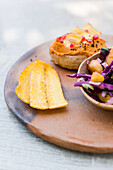 High angle of delicious sandwiches served with vegetables and fresh salad in bowl near banana crisp on wooden plate on table