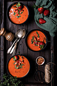 Komposition von oben mit köstlicher hausgemachter Tomaten-Erdbeer-Gazpacho-Suppe, serviert in Schalen auf einem rustikalen Holztisch