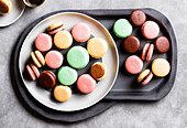 Delicious sweet assorted macaroons with chocolate cream placed on white plate in cafe