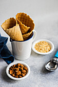 Waffle cones and nuts for ice cream preparation on concrete table with white concrete background with towel