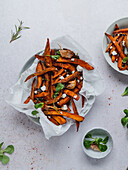 High angle of delicious sweet potato fries with sour cream and herbs served on table