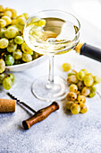 Georgischer Mtsvane-Wein im Glas und frische rohe Trauben auf rustikalem Tisch