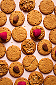 Top view of appetizing crispy biscuits with peanut butter with sesame seeds raspberries and nuts served on table as abstract background
