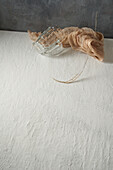 Glass cup and cloth placed with tree twig on beige and gray background