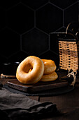 Appetizing fresh baked doughnuts placed on black plate on table against wicker basket