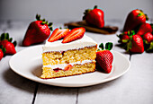 Yummy biscuit cake decorated with fresh strawberries placed on white ceramic plate