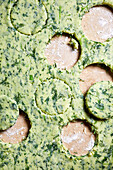 Top view recipe of healthy vegetarian potato spinach gnocchi dough with cut out circles