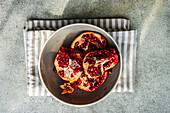 From above ripe organic pomegranate fruit on the ceramic plate and tea towel