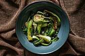 Top view of ceramic bow of yummy fried bok choy with sesame placed on brown fabric