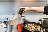 Crop unrecognizable cook putting raw lobster into metal pot with boiling hot water on stove with clams in frying pan