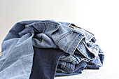 Pile of blue colored folded and crumple denim pants placed in light studio