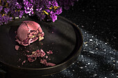 Von oben Strauß frischer violetter Blumen auf Marmortisch neben Teller mit zerdrückter Makrone am Morgen