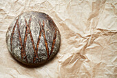 Top view of delicious homemade round shaped sourdough bread with crispy crust placed on parchment paper
