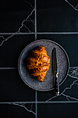 Von oben frisch gebackenes Croissant mit Marmelade auf dem gefliesten schwarzen Betontisch