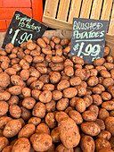 From above of many brushed potatoes in box with price placed on stall in local Australian market