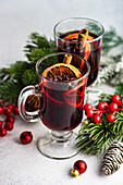 Mulled wine with spices with holiday decoration on white concrete background