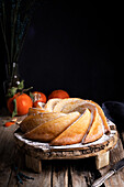 Appetizing sweet homemade bundt cake sprinkled with white sugar powder served on rustic wooden table with fresh tangerines