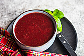 Rote-Bete-Cremesuppe, serviert in einer schwarzen Keramikschale mit frischem Basilikumkraut
