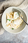 From above traditional ukrainian dumplings stuffed with potato, well-known vareniki, served in a bowl with sour cream