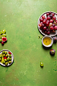 Draufsicht auf eine Traube köstlicher, frischer, saftiger, roter und grüner Weintrauben auf einem Teller mit grünem Hintergrund
