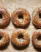 Draufsicht auf leckere gebackene Bagels mit Samen auf Pergamentpapier in einer Bäckerei