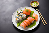 Delicious sushi rolls with raw salmon served on lettuce leaf on ceramic plate near onion in bowl with chopsticks