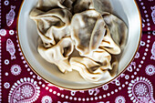 Georgian khinkali served in the bowl on traditional Supra tablecloth covered with black pepper spice