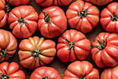 Top view of branch of delicious fresh big red tomatoes placed on cardboard box